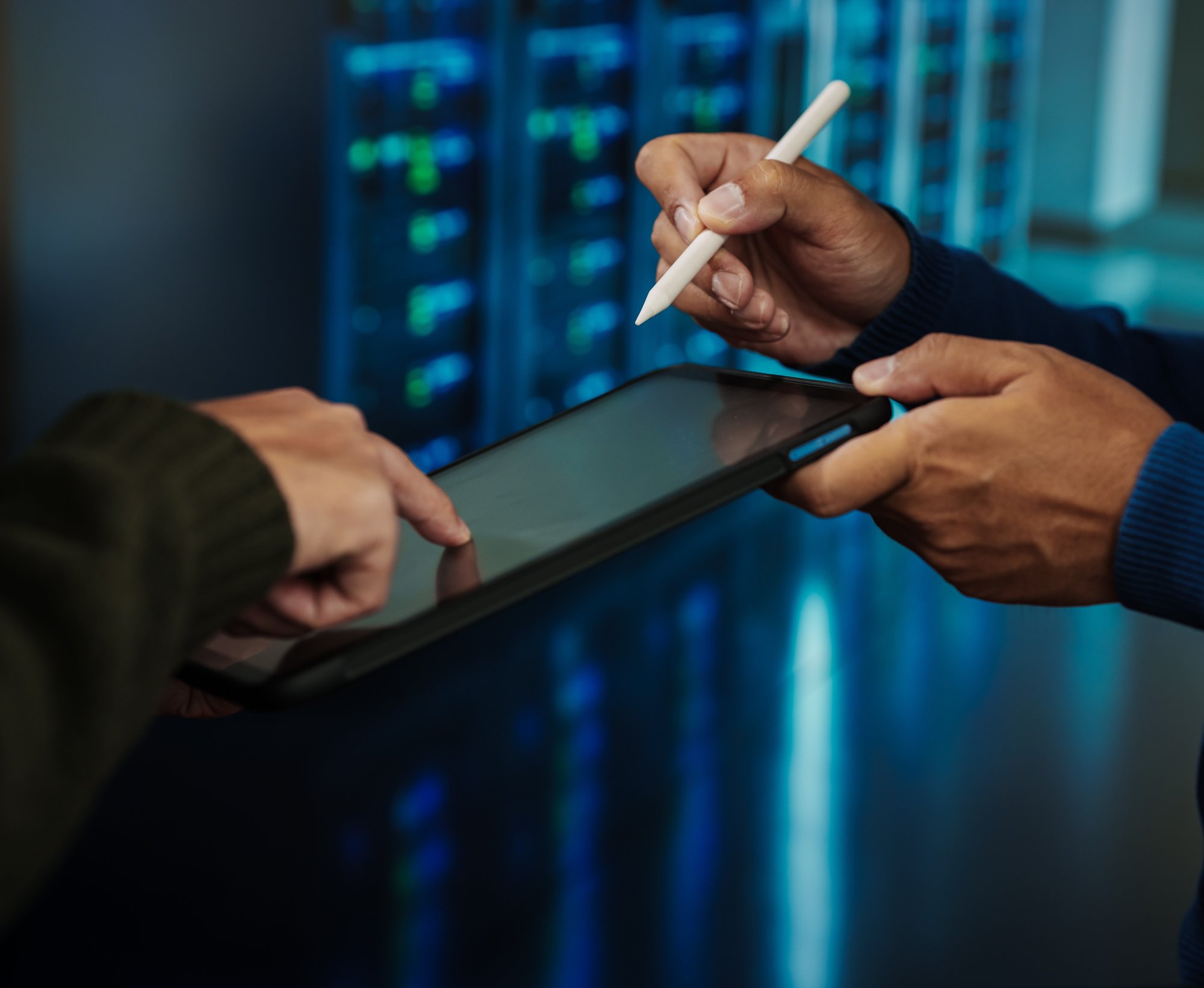 hands marking something and pointing at something on tablet in server room