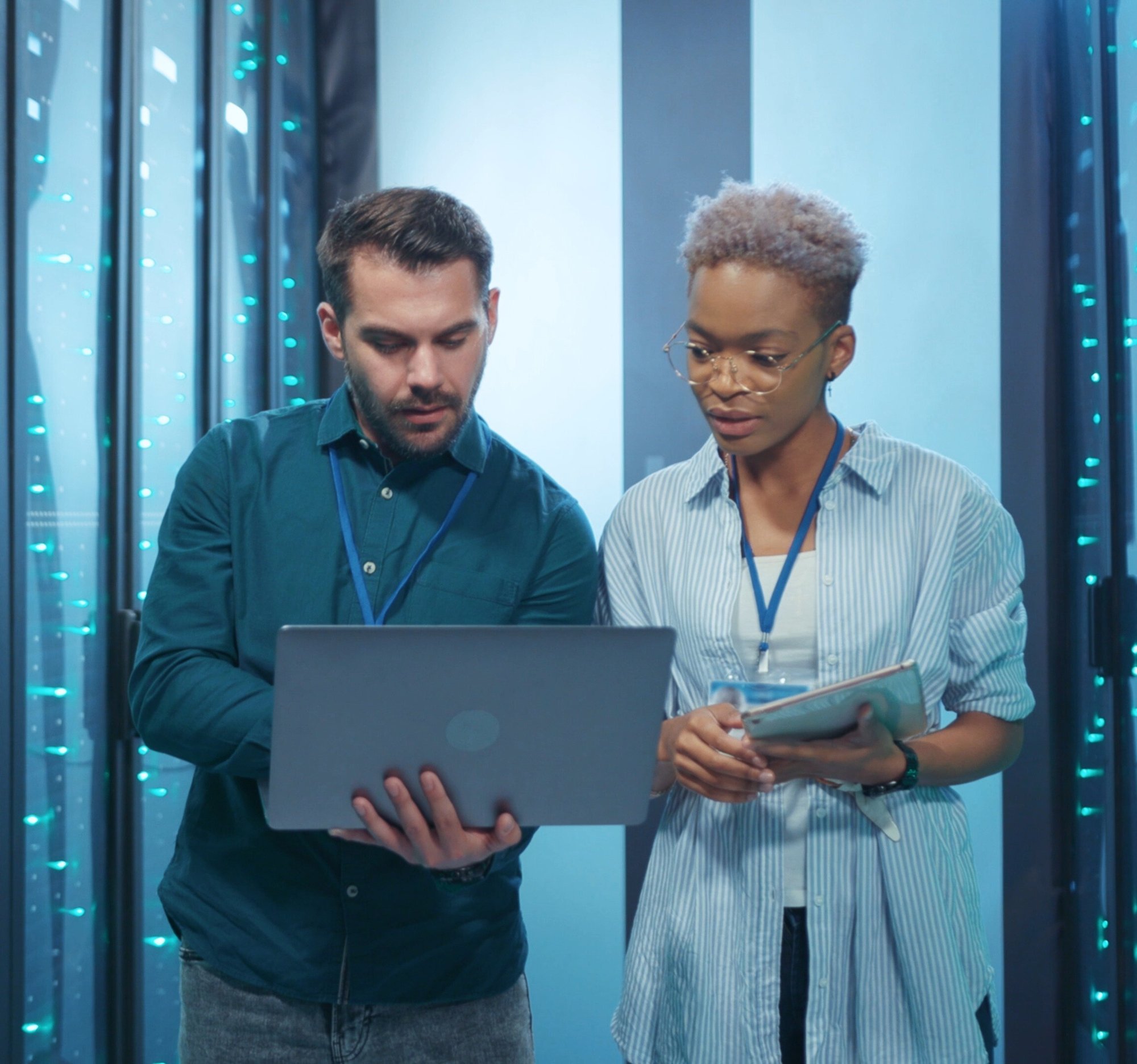 Two professionals looking at laptop in server room