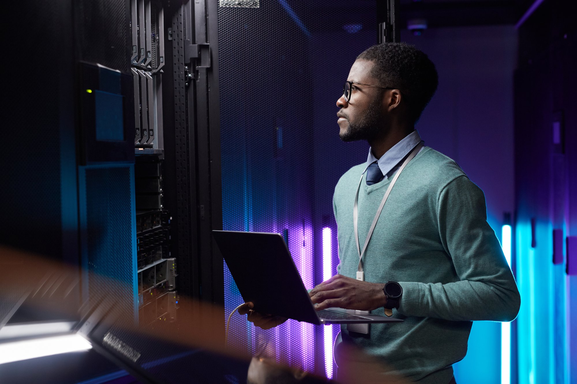 Professional male tech services provider looking at data rack