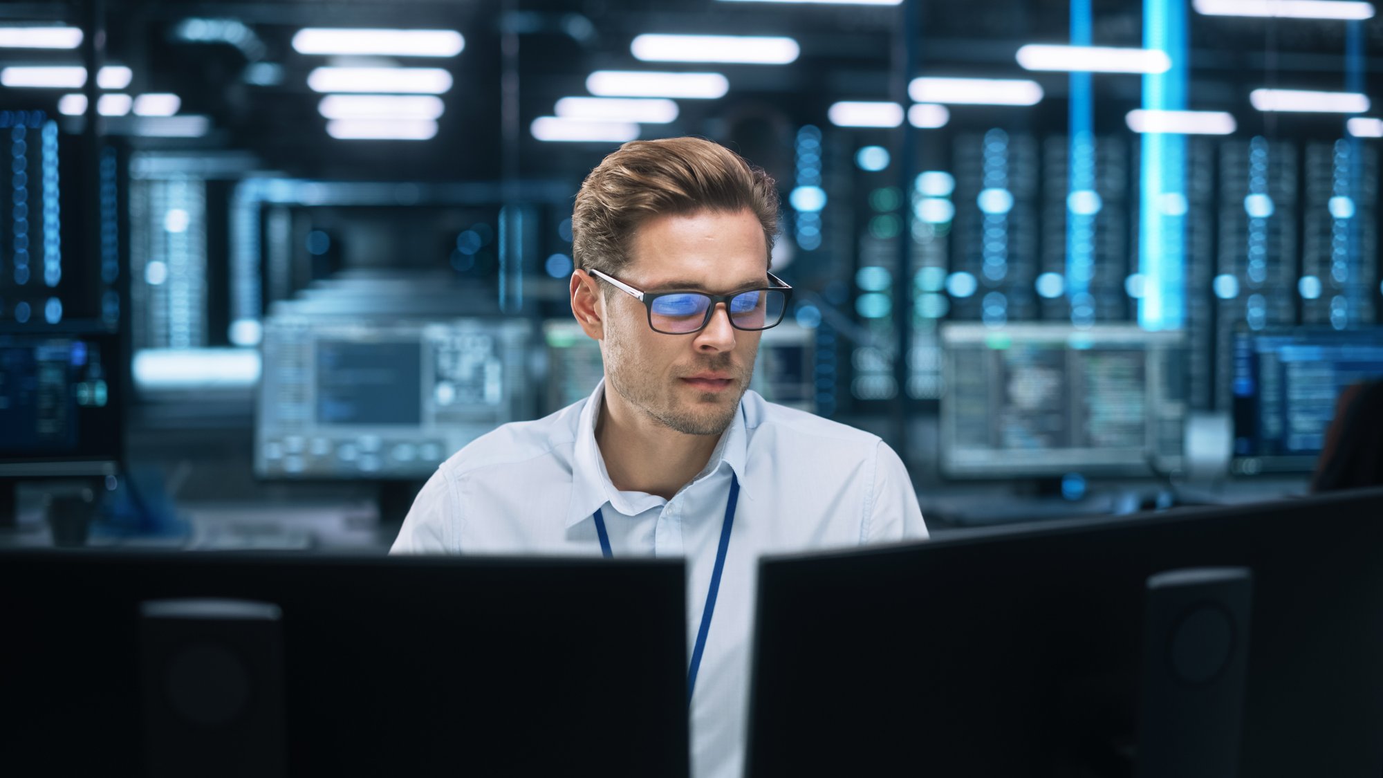 man in server room typing on computers