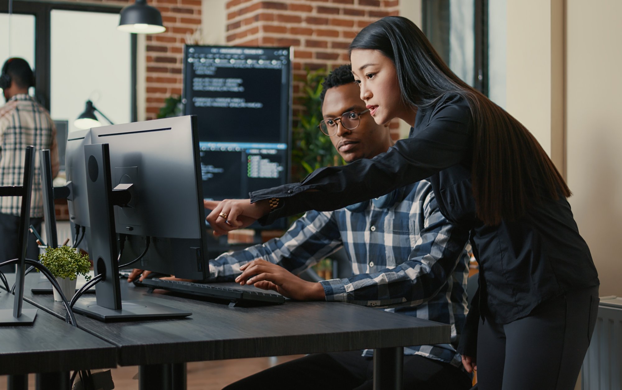 two tech employees consulting computer in office