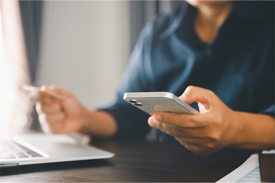 professional using phone while sitting with laptop