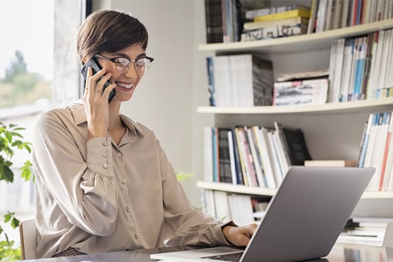 professional working on laptop while using mobile device