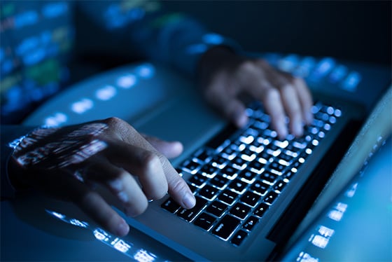 cyber hacker typing on laptop at night