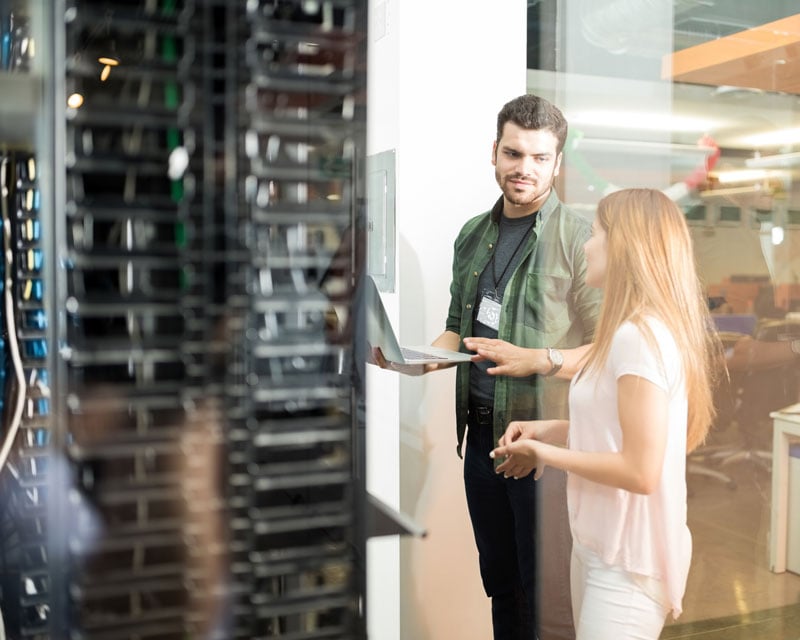 Two colleagues standing inside a data center.