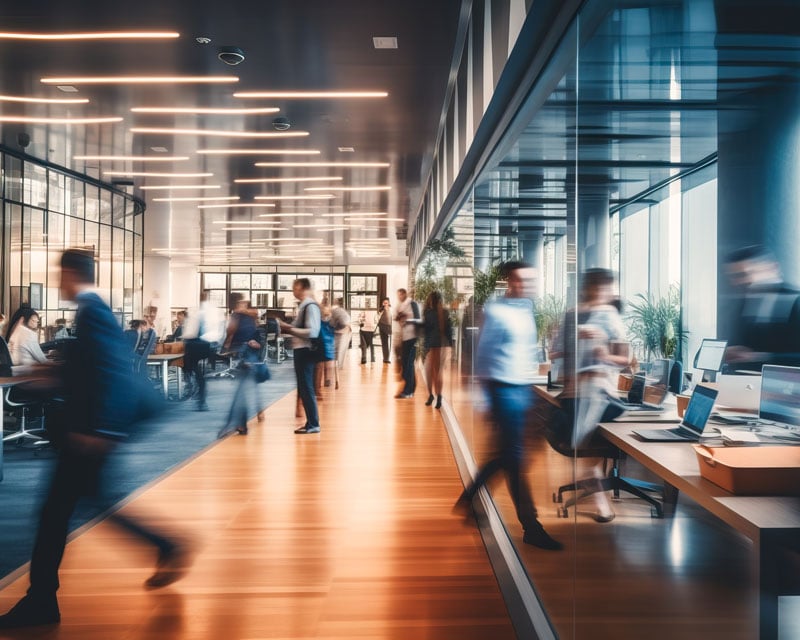 A bunch of professionals quickly moving around an office.