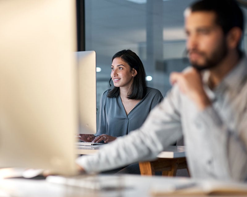 Two professionals working on desktop computers in an office.