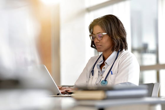 A healthcare professional working on a laptop, utilizing IT security services to safeguard patient data.