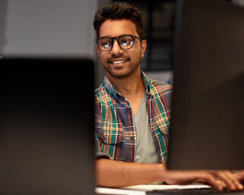 A person working on computer with multiple screens.