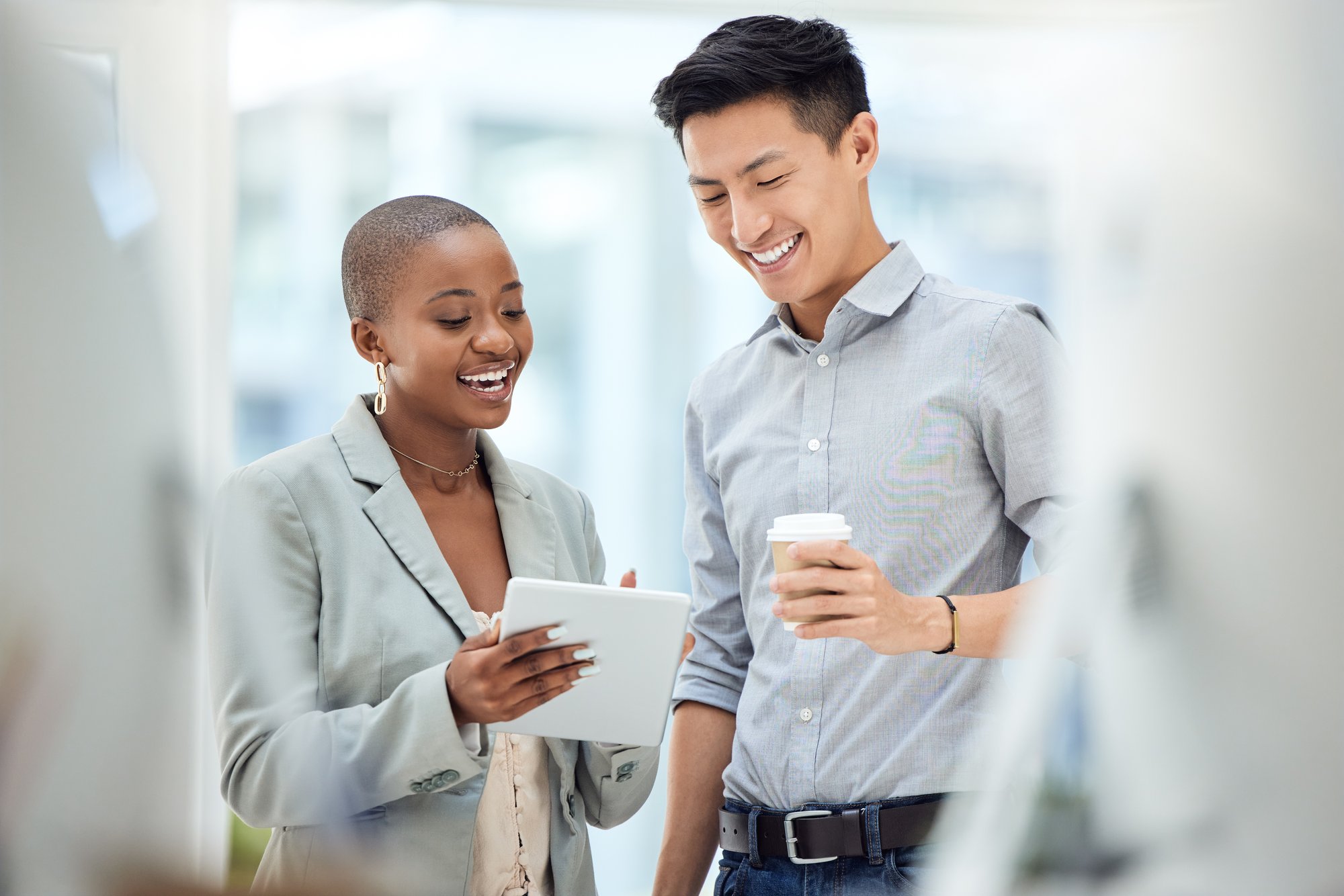 Woman and man smiling, talking, looking at tablet